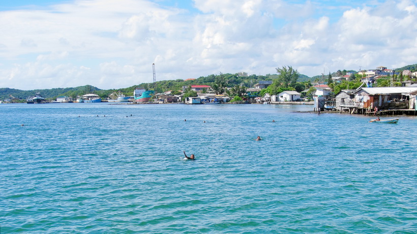 Children swimming out to wave to the Catamara coming by and hoing to have some soda tossed to them.