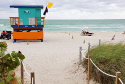 Couple enjoying their morning coffee on the beach at Miami Beach, Florida, under a beach umbrella.